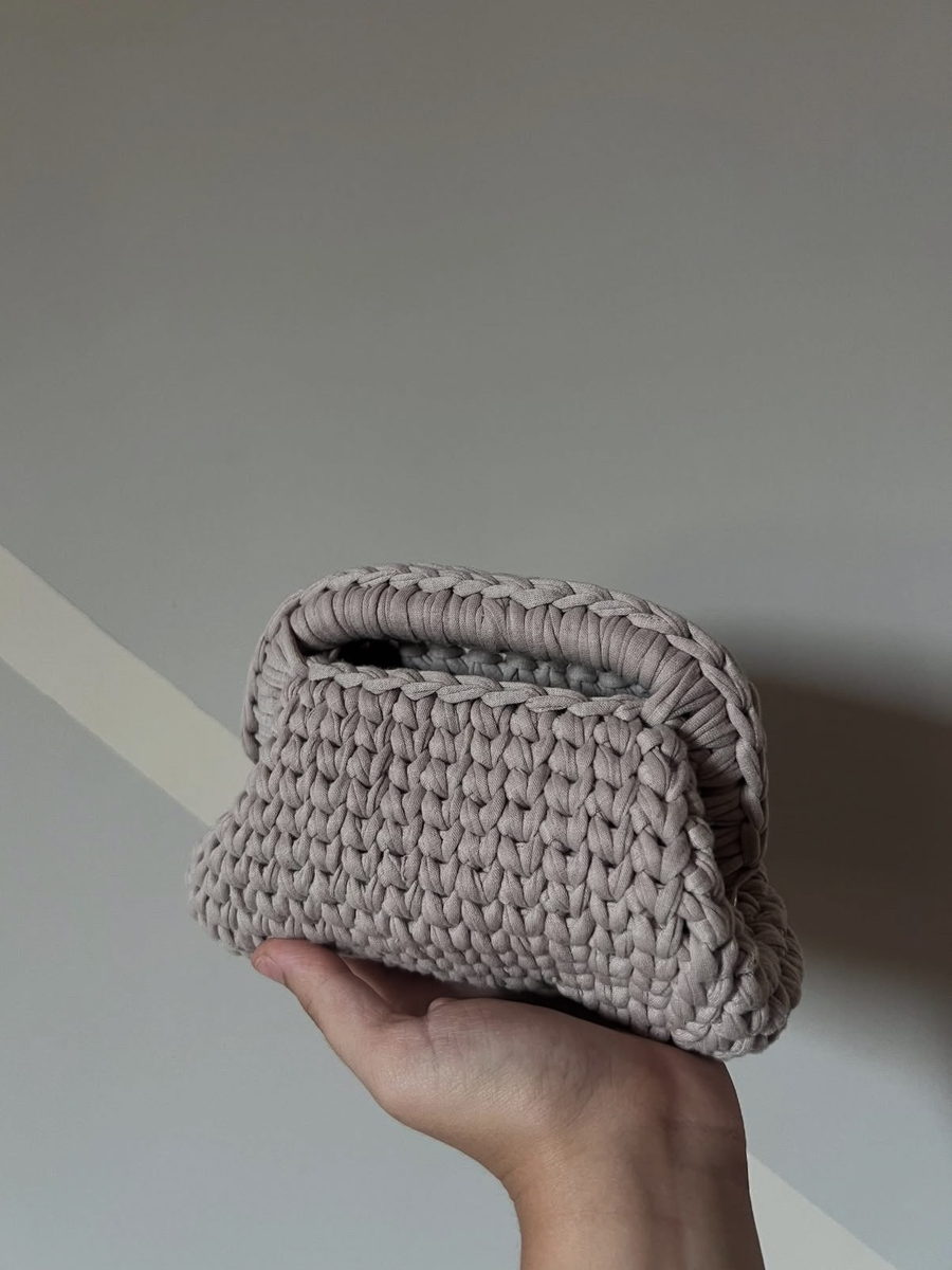Nuvola: pouch morbida in filato tortora con bordo intrecciato, tenuta in mano